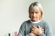 Eine ältere Frau hält sich die Hände vor die schmerzende Brust Eine ältere Frau hält sich die Hände vor die schmerzende Brust